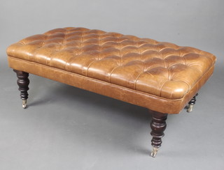 A Victorian style rectangular stool, the seat upholstered in brown buttoned hide, raised on turned supports ending in chrome caps and casters 43cm h x 123cm l x 73cm w  