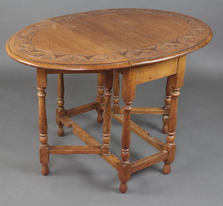 An oval carved light oak drop flap gateleg tea table raised on turned and block supports 72cm x 77cm x 35cm when closed x 108cm when open  