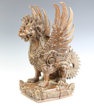 A Burmese carved hardwood figure of a seated winged mythical beast raised on a square base 45cm x 19cm x 23cm 