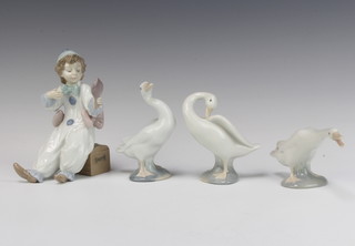 A Lladro figure of a seated boy clown 15cm together with 3 Lladro geese 