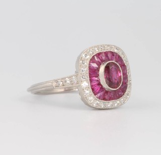 A platinum, ruby and diamond ring the oval cut ruby surrounded by calibre cut rubies and brilliant cut diamonds size L 1/2 
