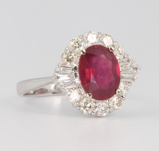 An 18ct white gold ruby and diamond ring, the treated oval shaped ruby 2.68ct surrounded by brilliant and tapered baguette diamonds 0.85ct, size N 