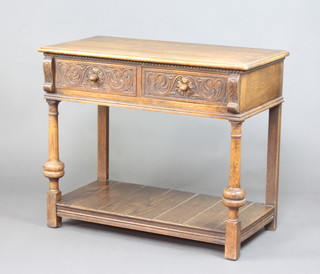 A 17th Century style carved oak side table with under tier, fitted 2 drawers with acorn handles, raised on cup and cover supports 76cm h x 92cm w x 36cm d  