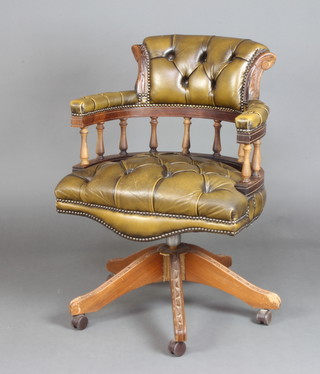 A mahogany Victorian style revolving office chair upholstered in red green buttoned leather with spindle turned decoration, raised on carved supports 