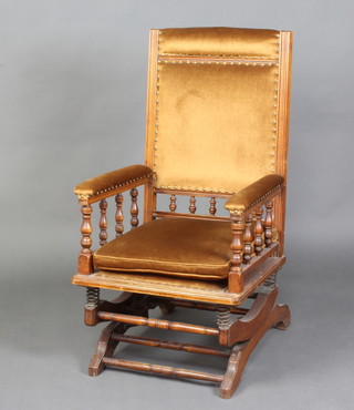 An Edwardian American walnut rocking chair with bobbin turned decoration, the seat and back upholstered in brown dralon 