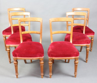A set of 6 Victorian light oak bar back dining chairs with plain mid rails and over stuffed seats, raised on turned and fluted supports