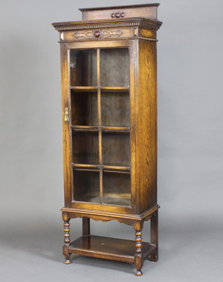 A 1920's oak display cabinet with raised back, moulded and dentil cornice, the interior fitted shelves enclosed by an astragal glazed panelled door, raised on turned and block supports with undertier 167cm h x 60cm w x 34cm d  