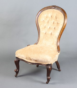 A Victorian carved mahogany show frame nursing chair upholstered in light coloured buttoned material, raised on cabriole supports 