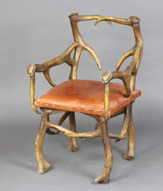 A faux antler armchair with leather upholstered seat, raised on faux antler (fibreglass) supports (damage to the back) 