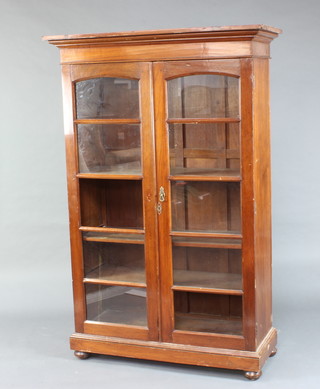 A hardwood display cabinet with moulded cornice, fitted shelves enclosed by arched panelled doors, raised on a platform base 185cm h x 121cm w x 48cm d (2 glass panels missing, 1 brass handle missing) 