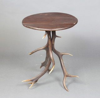 A circular mahogany occasional table raised on an antler base 66cm h x 50cm diam. 