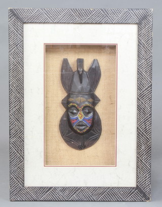 A carved African mask with bead work decoration contained in a carved hardwood frame 70cm x 52cm 