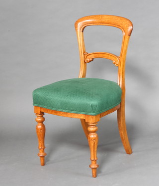 A Victorian light oak bar back chair with carved mid rail and over stuffed seat, raised on turned and fluted supports