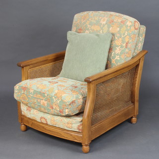 An Ercol elm show frame single cane bergere armchair, the seat and back upholstered in green sculptured Dralon 