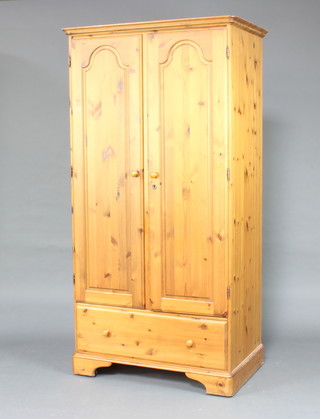 A Ducal pine wardrobe enclosed by panelled doors, the base fitted a drawer, raised on bracket feet 192cm h x 99cm w x 60cm d  