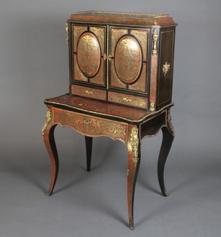 A 19th Century French ebonised and red boulle salon cabinet, the upper section with pierced brass 3/4 gallery, fitted a cupboard, shelf and 2 short drawers enclosed by a pair of oval panelled doors above 2 short and 1 long drawers with writing slide, raised on cabriole supports 132cm h x 79cm w x 52cm d  