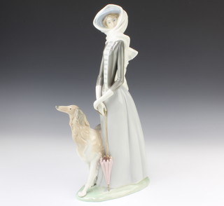 A Lladro figure of a lady standing with a parasol  and an Afghan hound at her side 39cm 