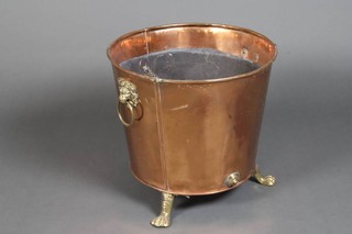 A circular waisted copper log basket with brass lion mask handle raised on brass hoof supports 43cm h x 47cm 