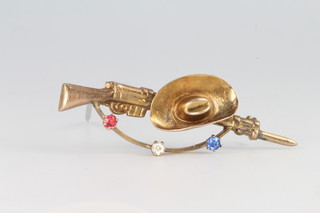 A 9ct yellow gold gem set novelty bar brooch in the form of a rifle and stetson, 2.5 grams 