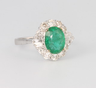 An 18ct white gold diamond and emerald cluster ring, the centre emerald surrounded by brilliant and tapered baguette cut diamonds, size N 