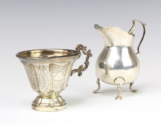 An Edwardian silver baluster cream jug on pad feet London 100, a chased repousse silver cup, 145 grams 