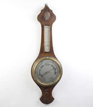 A 1930's aneroid barometer and thermometer with silvered 20cm dial, contained in a carved oak wheel case 