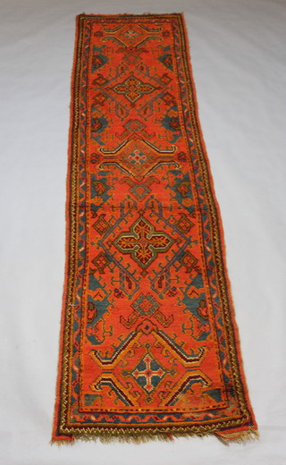 An orange and green ground Turkey runner with stylised medallions to the centre within a multi row border, 355cm x 93cm 