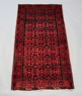 A red and green ground Afghan rug with all over geometric design within a multi row border 193cm x 100cm 