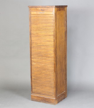 A 1930's oak filing cabinet fitted trays enclosed by a tambour shutter raised on a platform base 150cm h x 46cm w x 41cm 