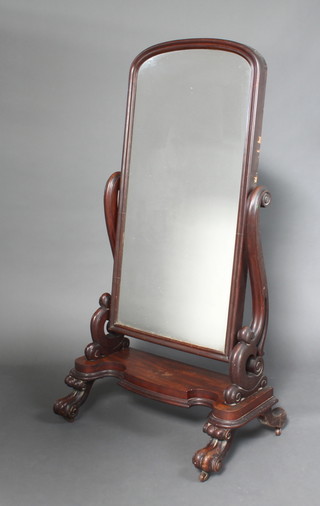 A Victorian arched plate cheval mirror contained in a mahogany swing frame with paw supports 163cm h 89cm w x 56cm d 