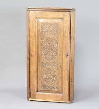 An 18th/19th Century carved oak hanging corner cabinet fitted shelves enclosed by a panelled door 115cm h x 59cm w x 35cm d 