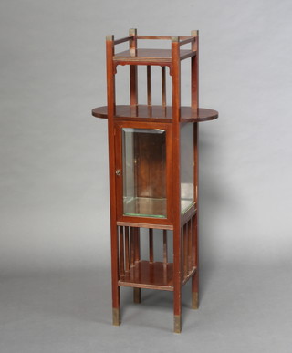 An Edwardian Art Nouveau Liberty style display cabinet, the upper section fitted an oval shelf above a cabinet enclosed by a bevel glazed panelled door, the base with recess 130cm h x 57cm w x 31cm d 