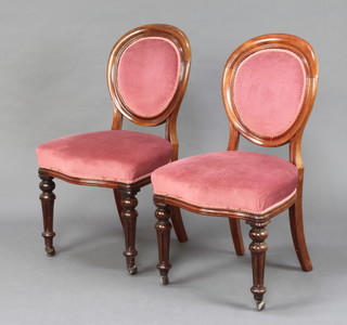 A pair of Victorian mahogany show frame chairs upholstered in pink Dralon, raised on turned and fluted supports 