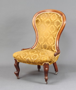 A Victorian mahogany show frame nursing chair upholstered in gold material, raised on cabriole supports 
