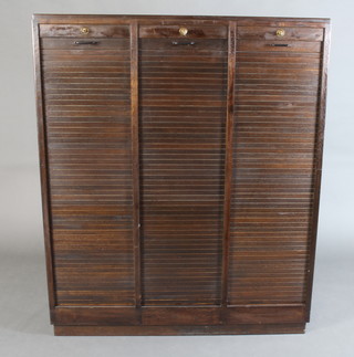 A 1930's triple section oak filing cabinet enclosed by a tambour shutter, raised on a platform base 150cm h x 125cm w x 36cm d 