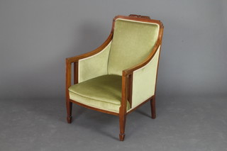 An Edwardian bleached and inlaid mahogany show frame armchair upholstered in green material raised on square tapered supports ending in spade feet 