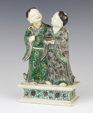 A 19th Century Chinese famille verte group of 2 standing gentleman, 1 holding a lidded box the other a gnarled staff, raised on a rectangular base 20cm 
