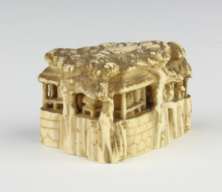 A Meiji period Japanese carved ivory Netsuke in the form of a building with figures seated inside, raised on a rocky outcrop, signed, 4cm 