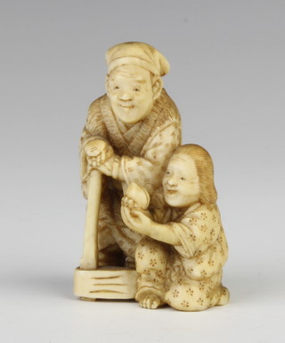 A Meiji period Japanese carved ivory okimono of a standing man with a child kneeling at his feet holding a peach, signed 5cm 