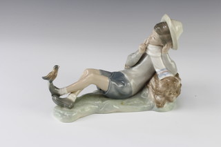 A Lladro figure of a boy resting against  a log with a bird on his foot 23cm 