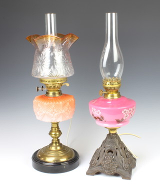 A Victorian orange opaque glass oil lamp reservoir complete with shade and chimney,  58cm h x 17cm together with 1 other with opaque pink and floral glass reservoir raised on a pierced metal base 60cm h x 17cm diam., both converted to electricity  
