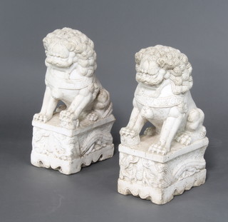 A pair of antique style Chinese carved white marble figures of shi shi raised on scroll bases 62cm 