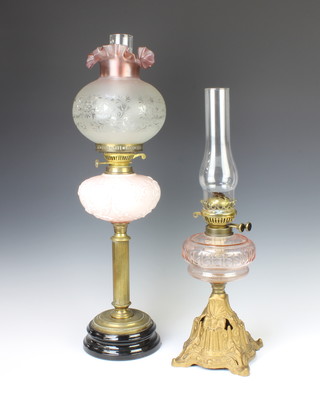 A Victorian faceted peach glass reservoir raised on a pierced iron stand complete with chimney 58cm x 18cm together with a pink opaque glass oil lamp reservoir with pink tinted glass shade and chimney, raised on a reeded brass column 71cm h x 15cm 