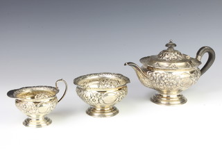An Edwardian repousse silver bachelor tea set comprising teapot, sugar bowl and cream jug decorated with flowers and vacant cartouche, Sheffield 1903, gross 730 grams
