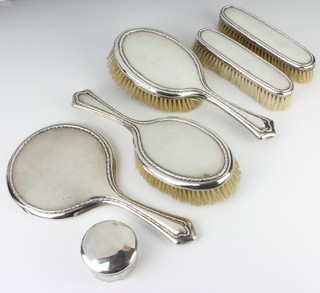 A silver backed dressing table set comprising hand mirror, 2 hair brushes, 2 clothes brushes, Sheffield 1921 and a silver lidded jar 