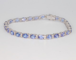 An 18ct white gold tanzanite and diamond line bracelet, the oval tanzanites approx. 9.22ct, the brilliant cut diamonds approx. 0.65ct, 18cm 