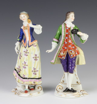 A pair of early 20th Century Continental figures of a lady and gentleman holdings masks 19cm 