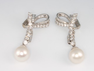 A fine pair of platinum, diamond and detachable baroque pearl bow ear drops, comprising 34 brilliant cut graduated diamonds and 40 baguette cut tapered diamonds each terminating in a baroque pearl 15mm, the overall measurement 60mm, the gross weight 26 grams 