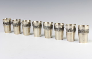A set of 8 Chinese silver tots decorated with figures in landscapes 6cm, 321 grams
