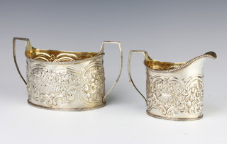 A George III silver repousse cream jug and sugar bowl decorated with vases of flowers, London 1806, 437 grams 